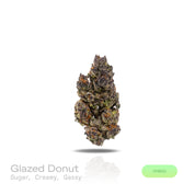 PUFFY Glazed Donut is a balanced hybrid THCa strain, born from the flavorful fusion of Grape Slushie and Purple Punch. The aroma opens with sweet, sugary notes, followed by a smooth creamy richness and finished with a distinct gassy edge that adds depth and complexity. Visually, dense olive-green buds with purple accents and fiery orange pistils are coated in sticky, glistening trichomes. Consumers often report a gradual cerebral euphoria and uplifted mood, paired with deep full-body relaxation, leaving the