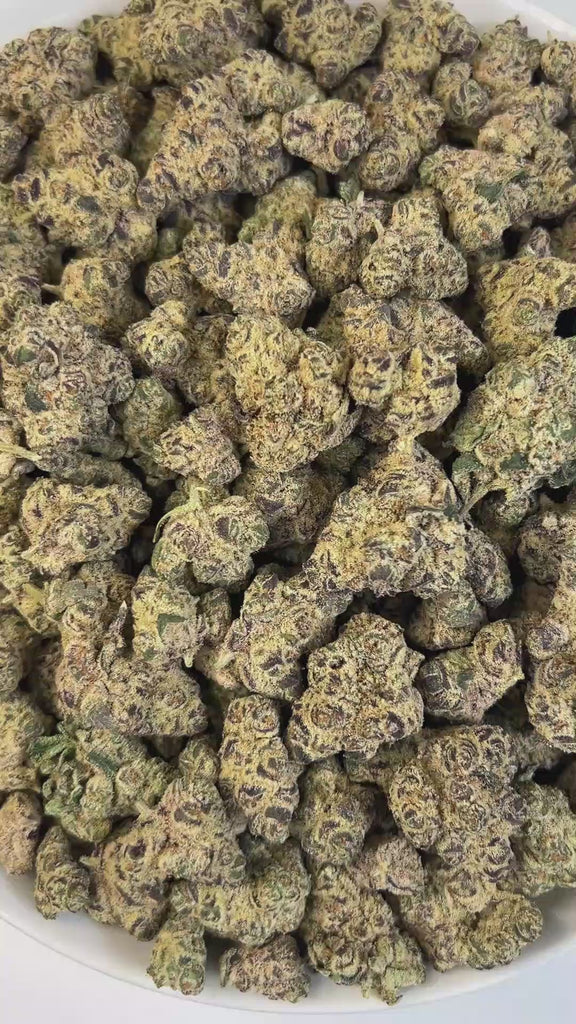 PUFFY Drippin Ain’t Eazy is a hybrid THCa strain, a lively and flavorful cross between Drip Station and Gary Poppins. A rich and complex aroma featuring bold diesel notes, layered with musky undertones, complemented by hints of ripe fruitiness, creamy smoothness, and a subtle, lingering sweetness. Visually, dense buds glisten with frosty trichomes, showcasing deep purple and pale green hues. Consumers often describe it as delivering a balanced experience that soothes and relaxes while stimulating creativity