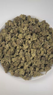 PUFFY Carbon Fiber is a balanced hybrid THCa strain, created from a potent blend of Grape Pie, Biscotti, and Cookies & Cream. The aroma blends creamy sweetness with sharp chemical tones and a grounding woody finish, resulting in a bold and complex scent profile. Visually, the buds are dense and striking, featuring deep green and purple hues, coated in frosty trichomes and accented with bright orange pistils. Consumers often describe the smoke as creamy and smooth, with a powerful high that feels giggly, tin