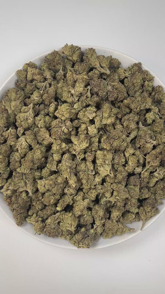 PUFFY Carbon Fiber is a balanced hybrid THCa strain, created from a potent blend of Grape Pie, Biscotti, and Cookies & Cream. The aroma blends creamy sweetness with sharp chemical tones and a grounding woody finish, resulting in a bold and complex scent profile. Visually, the buds are dense and striking, featuring deep green and purple hues, coated in frosty trichomes and accented with bright orange pistils. Consumers often describe the smoke as creamy and smooth, with a powerful high that feels giggly, tin