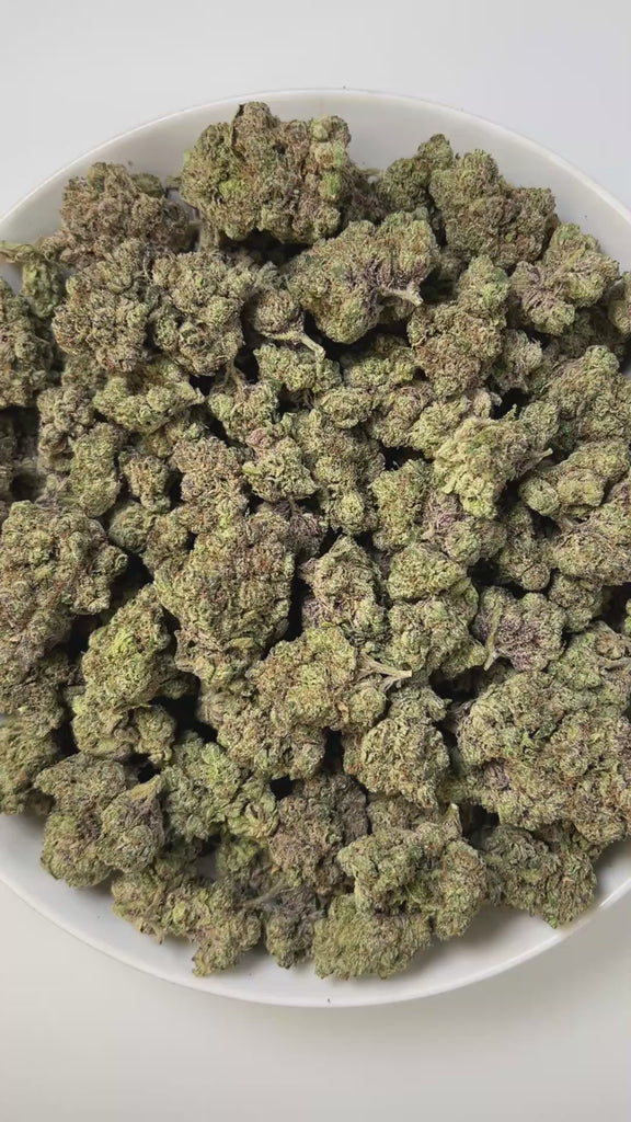 PUFFY Blueberry Jam is an indica-dominant hybrid THCa strain, born from the legendary cross between Blueberry and Northern Lights. The aroma unfolds with sweet blueberries, sharp diesel undertones, and a refreshing hint of mint, creating a bold and intriguing scent profile. Visually, dense, chunky buds showcase forest green and golden tones, highlighted by orange pistils and deep blue hints, all dusted with sparkling trichomes. Consumers often describe a harmonious high that starts with a bright, uplifting 