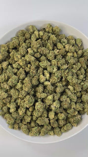PUFFY Mule Fuel (smalls) is a hybrid THCa strain, crafted from a genetic cross of Lurch and GMO Cookies. The aroma is bold and pungent, with sharp peppery notes, a robust garlicky undertone, and the unmistakable fuel-like scent of diesel. Visually, the buds are dense and compact, showcasing a vibrant olive-green color and a sparkling layer of trichomes. Consumers often report a deeply relaxing experience, characterized by waves of euphoria, soothing calm, a heavy, calming body melt, and a blissful sense of 