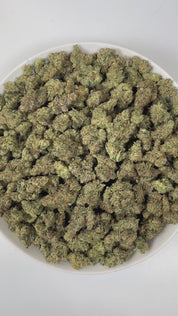 PUFFY UK Cheese is an indica-dominant hybrid THCa strain, renowned for its roots it showcases either a classic Skunk #1 expression or subtle hints of its iconic heritage. The aroma is a captivating blend of gassy, pine, and floral notes, creating a bold yet refreshing sensory experience. Visually, dense green buds with purple hues and fiery orange pistils are coated in sticky trichomes. Consumers often report euphoric, happy, and uplifted sensations paired with a relaxed, energetic feel that engages both th