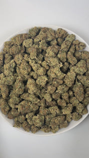 PUFFY GMO is an indica-dominant hybrid THCa strain, born from the legendary cross of Girl Scout Cookies and Chemdawg. The aroma opens with pungent notes of onion, intertwined with rich diesel and a hint of spicy undertones, creating a bold and unforgettable scent. Visually, the buds are dense and sticky, showcasing a striking mix of dark green and purple hues, drenched in thick crystalline trichomes and accented by fiery orange pistils. Consumers often report a deeply relaxing and calming effect that begins
