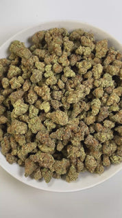 PUFFY Garlicane is an indica-dominant hybrid THCa strain, created by crossing GMO × Slurricane. The aroma combines a bold kick of pickled garlic with a sweet, candy-like finish, creating a uniquely savory-sweet profile. Visually, the buds are dense and deep green with purple hues, bright pistils, and a heavy frost of trichomes. Consumers often report a soothing body melt paired with gentle tingles, balanced by a calm, euphoric state of mind.
