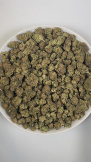 PUFFY Glitter Bomb is an indica-dominant hybrid THCa strain born from the flavorful cross of Grape Gas #10 and OGKB Blueberry Headband. The aroma profile is a rich blend of blueberry, earthy notes, and a skunky finish. Visually, the buds are dense and deep forest green with striking purple hues, bright orange pistils, and a heavy coating of sparkling white trichomes. Consumers report a bright rush of cerebral uplift that gently settles into a soothing, full-body calm, leaving them giggly, focused, and relax